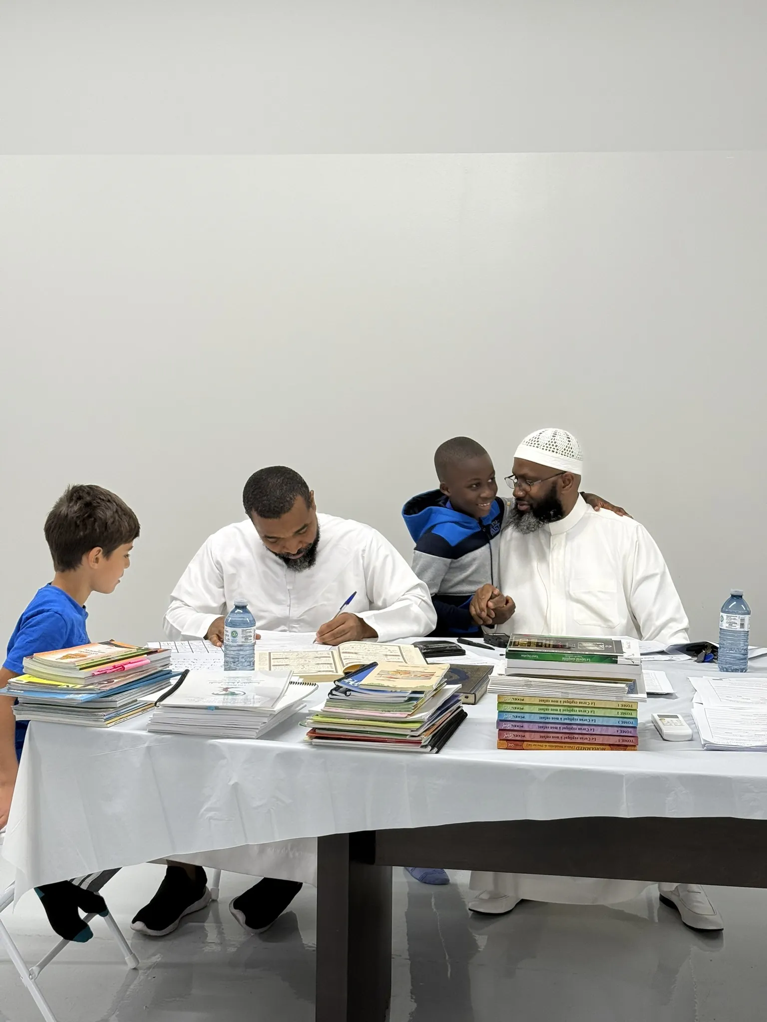 Des enfants et leurs professeurs autour des manuels.