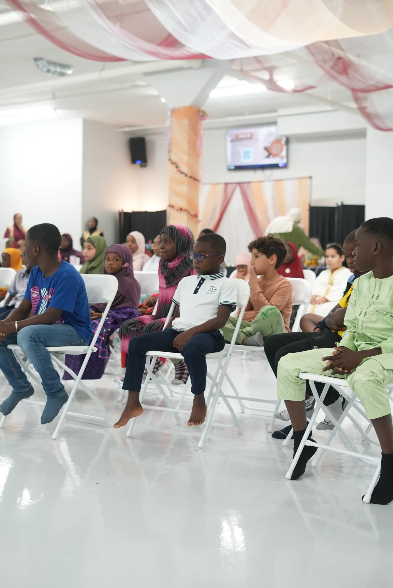 Des enfants assis en rangs dans la salle, attentifs.