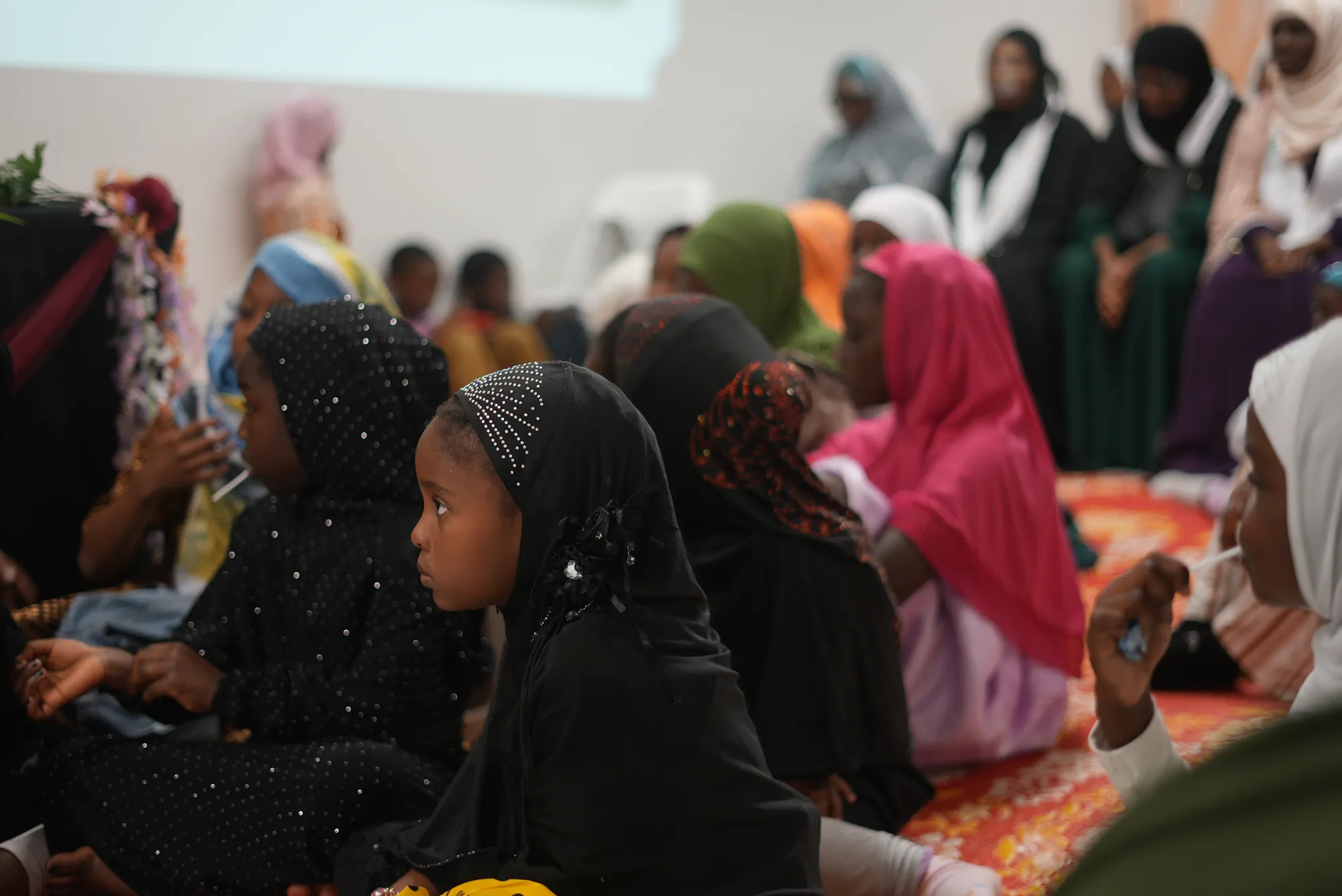 Des fillettes assises sur le tapis écoutent l’activité.
