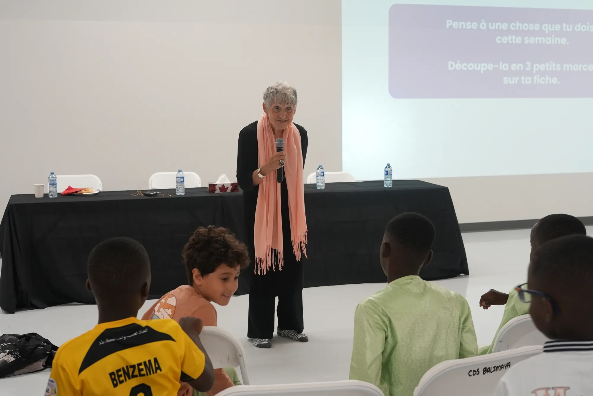 Une intervenante parle aux enfants assis devant elle.