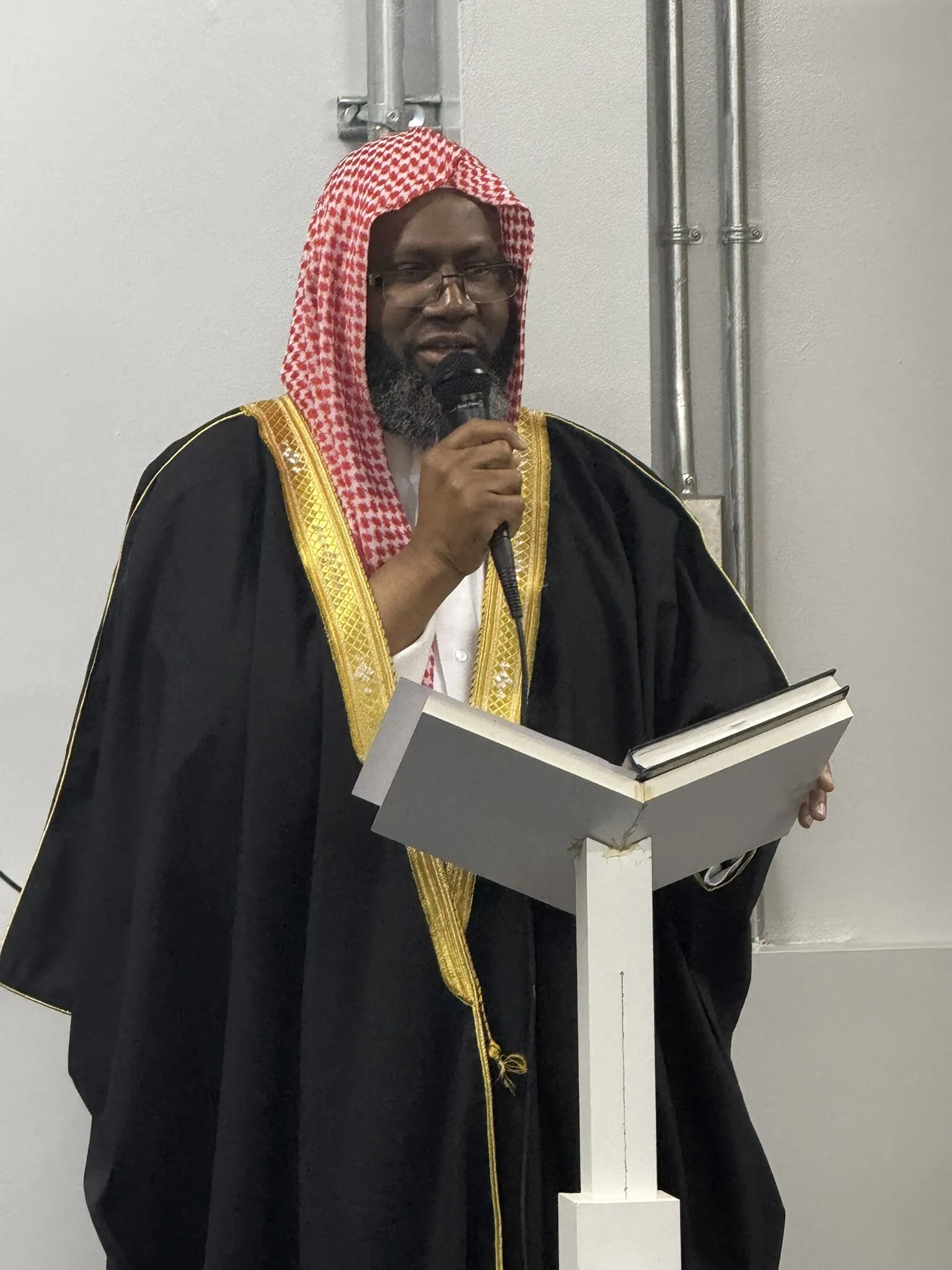 L'imam au pupitre, micro à la main.